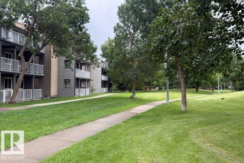 Exterior building featuring balconies with white railings, grey horizontal siding, and tan vertical siding accents - #307 6212 180 St Nw, Edmonton, AB - Outdoor