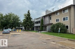 Multi-story residential building featuring a textured stucco exterior, multiple windows, and covered entrance - 