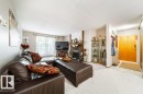 Living area featuring a brick fireplace with a wood mantle, a sliding glass door, and light-toned carpeting - #307 6212 180 St Nw, Edmonton, AB  - Indoor Photo Showing Living Room With Fireplace 
