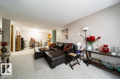 Spacious main living area featuring light-colored carpet flooring, neutral wall tones, and a textured ceiling - #307 6212 180 St Nw, Edmonton, AB - Indoor Photo Showing Living Room