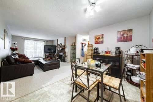 Open-concept living area featuring a brick fireplace, sliding glass door, ceiling fan, and carpeted flooring - #307 6212 180 St Nw, Edmonton, AB - Indoor Photo Showing Living Room