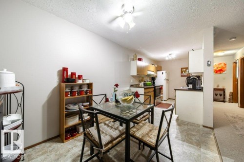 Bright dining area featuring tile flooring, a glass-top table, and a kitchen pass-through - #307 6212 180 St Nw, Edmonton, AB - Indoor Photo Showing Dining Room