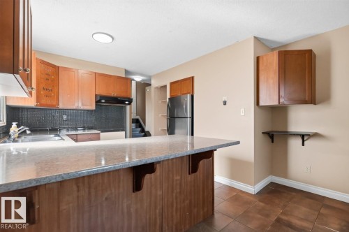 Kitchen featuring wood-finish cabinetry, stainless steel refrigerator, and a built-in oven - 4003 41 Avenue Nw, Edmonton, AB - Indoor Photo Showing Kitchen With Double Sink