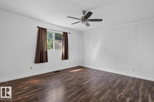 Spacious room featuring wood-finish flooring, white walls, and crown molding - 4003 41 Avenue Nw, Edmonton, AB - Indoor Photo Showing Other Room