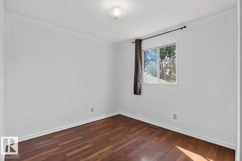 Room featuring wood-finish flooring, white baseboards, a white ceiling with a flush-mount light fixture, and a window with a dark curtain rod - 4003 41 Avenue Nw, Edmonton, AB - Indoor Photo Showing Other Room