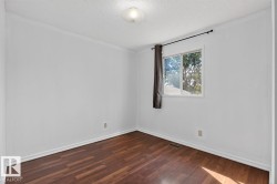 Room featuring wood-finish flooring, white baseboards, a white ceiling with a flush-mount light fixture, and a window with a dark curtain rod - 