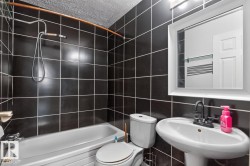 Bathroom featuring subway tile surround, pedestal sink with matte black faucet, and white framed mirror - 