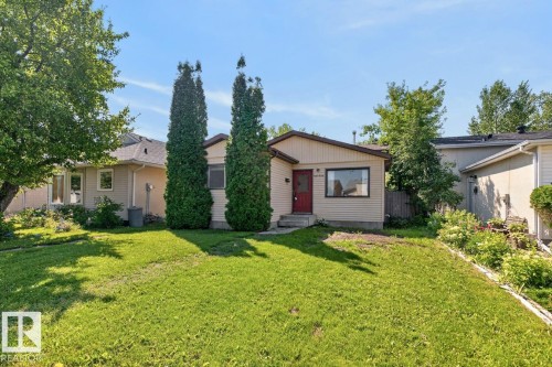 Single-story residence featuring light-colored siding, a dark red entry door, and a partially sloped roofline - 4003 41 Avenue Nw, Edmonton, AB - Outdoor