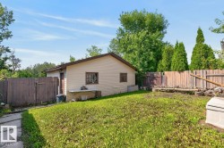 Expansive grassy yard with a beige-sided auxiliary building featuring a brown-trimmed roof - 