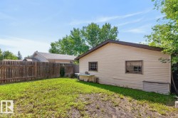Rear yard featuring a detached structure with light-colored siding, a brown trimmed roof, and multiple windows - 
