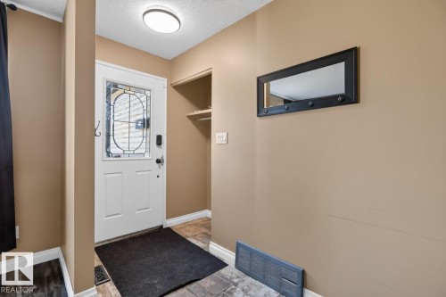 Entryway featuring a decorative glass-paneled door, sconce lighting, and a built-in storage nook - 4003 41 Avenue Nw, Edmonton, AB - Indoor Photo Showing Other Room