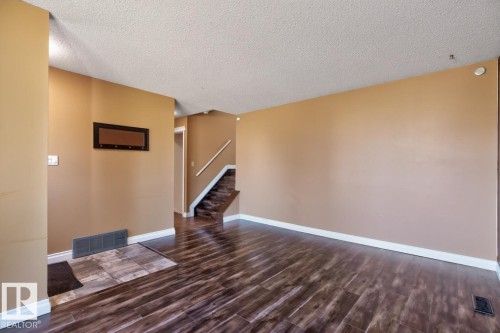 Spacious room featuring wood-finish flooring, light tan wall paint, and white baseboards - 4003 41 Avenue Nw, Edmonton, AB - Indoor Photo Showing Other Room