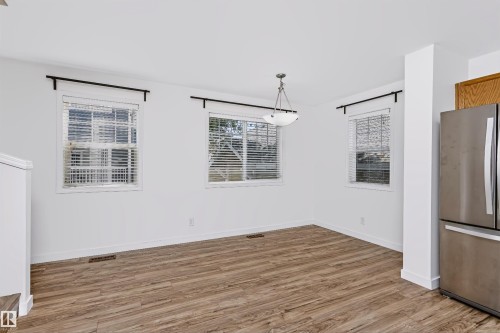 Dining space featuring wood-finish flooring, white walls, and a contemporary semi-flush mount light fixture - #66 8304 11 Av Sw, Edmonton, AB - Indoor Photo Showing Other Room