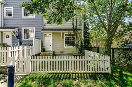 Exterior featuring light green horizontal siding and a white picket fence - #66 8304 11 Av Sw, Edmonton, AB - Outdoor