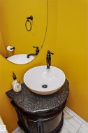 Vanity with a vessel sink, dark granite countertop, and ornate wood-finish cabinetry - 