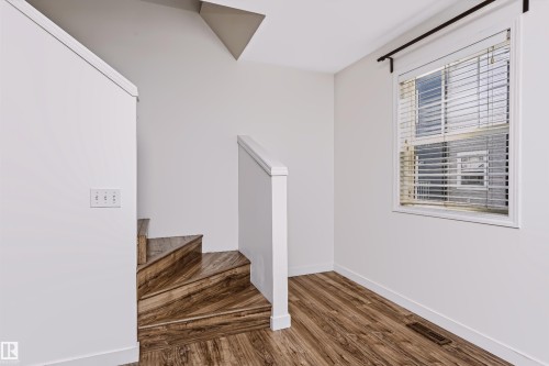 Staircase featuring wood-finish treads and risers with white painted handrails - #66 8304 11 Av Sw, Edmonton, AB - Indoor Photo Showing Other Room