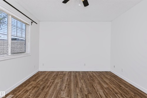 Spacious room featuring wood-finish flooring and a ceiling fan - #66 8304 11 Av Sw, Edmonton, AB - Indoor Photo Showing Other Room