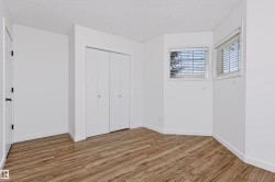 Room with wood-finish flooring, two windows with blinds, and white bi-fold closet doors - 