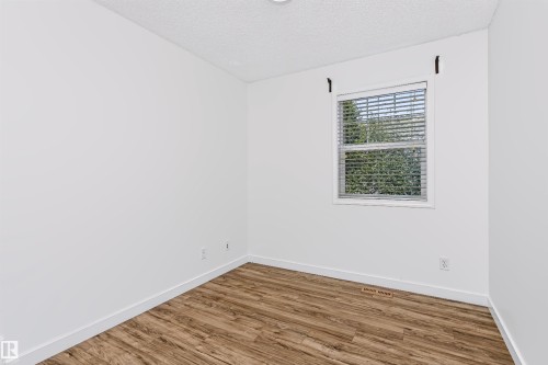 Room featuring wood-finish flooring, white walls, and a window with blinds - #66 8304 11 Av Sw, Edmonton, AB - Indoor Photo Showing Other Room