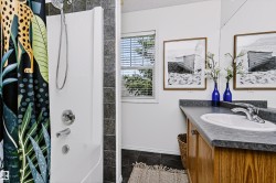 Bathroom with a white shower enclosure, chrome fixtures, and dark tiled walls - 