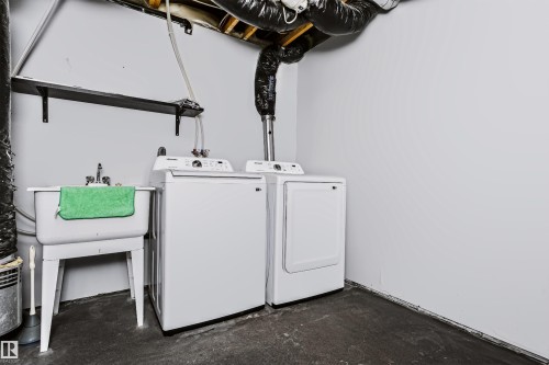 Dedicated laundry area featuring a utility sink, washer, and dryer - #66 8304 11 Av Sw, Edmonton, AB - Indoor Photo Showing Laundry Room