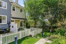 Rear exterior featuring a private patio, white picket fence, and a concrete pathway leading to a treed yard - #66 8304 11 Av Sw, Edmonton, AB  - Outdoor 