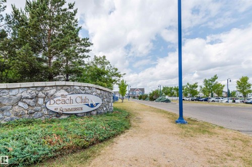Stone wall signage for "The Beach Club at Summerside" with mature landscaping - #66 8304 11 Av Sw, Edmonton, AB - Outdoor With View
