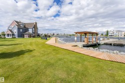 Expansive green lawn with a wooden boardwalk leading to a waterfront pier - 