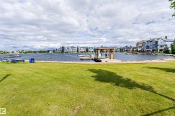 Expansive waterfront property featuring a manicured lawn, a private dock with a covered boat slip, and a stone-lined shoreline - 