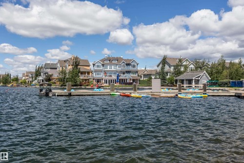 Waterfront property featuring an expansive private dock with multiple berthing stations, a spacious upper deck, and a detached waterside boathouse - #66 8304 11 Av Sw, Edmonton, AB - Outdoor With Body Of Water With View