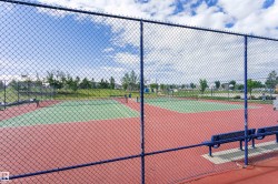 Tennis court featuring a hard surface, red and green playing area, chain-link fencing, and integrated benches - 
