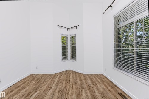 Room featuring wood-finish flooring, white walls, and multiple windows with horizontal blinds - #66 8304 11 Av Sw, Edmonton, AB - Indoor Photo Showing Other Room
