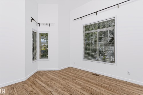 Spacious room featuring vaulted ceilings, a prominent large window, and an additional bay window array - #66 8304 11 Av Sw, Edmonton, AB - Indoor Photo Showing Other Room