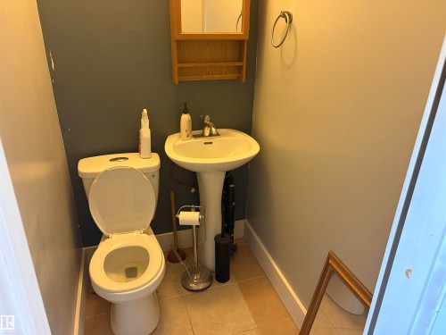 Compact powder room featuring a pedestal sink with chrome faucet, a white toilet, and tile flooring - 4620 Maria Drive, Smoky Lake Town, AB - Indoor Photo Showing Bathroom