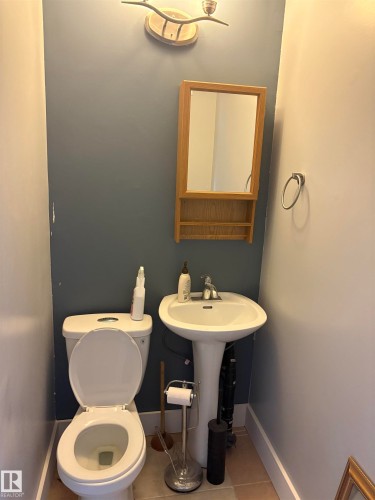 Pedestal sink with chrome faucet, complemented by a wall-mounted wooden mirror cabinet and overhead vanity lighting - 4620 Maria Drive, Smoky Lake Town, AB - Indoor Photo Showing Bathroom