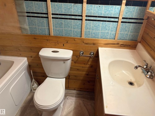 Bathroom with wood paneling, a white toilet, and a white integrated sink vanity - 4620 Maria Drive, Smoky Lake Town, AB - Indoor Photo Showing Bathroom