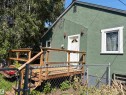 Green textured exterior with white trim windows and a white entry door - 4620 Maria Drive, Smoky Lake Town, AB  - Outdoor With Deck Patio Veranda 