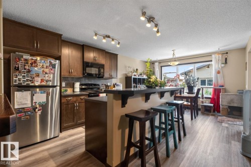 Kitchen featuring dark wood-finish cabinetry, black countertops, and a full suite of appliances - 3627 12 Street Nw, Edmonton, AB - Indoor Photo Showing Kitchen