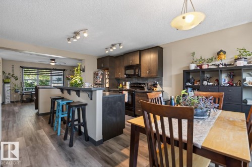 Open-concept kitchen and dining area featuring wood-finish flooring, dark wood cabinetry, and a breakfast bar with built-in shelving - 3627 12 Street Nw, Edmonton, AB - Indoor Photo Showing Dining Room