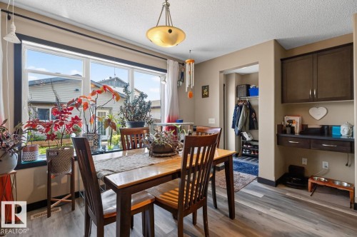 Dining area featuring a large window, contemporary ceiling light fixture, wood-finish flooring, built-in cabinetry, and a recessed entryway - 3627 12 Street Nw, Edmonton, AB - Indoor Photo Showing Dining Room