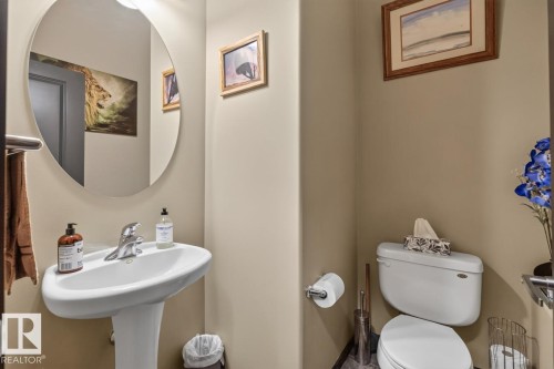 Pedestal sink with chrome faucet and circular mirror - 3627 12 Street Nw, Edmonton, AB - Indoor Photo Showing Bathroom