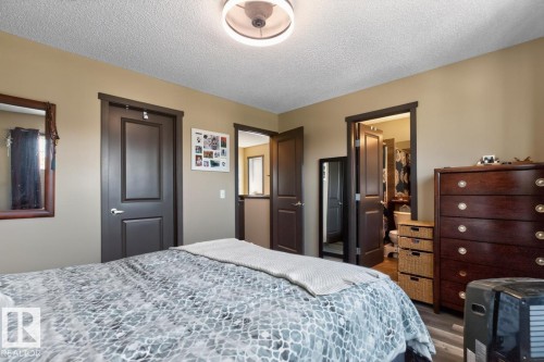 Neutral-toned room featuring a ceiling fan with integrated lighting, dark wood-finish doors and trim, and wood-finish flooring - 3627 12 Street Nw, Edmonton, AB - Indoor Photo Showing Bedroom