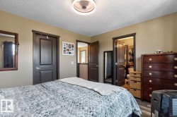 Neutral-toned room featuring a ceiling fan with integrated lighting, dark wood-finish doors and trim, and wood-finish flooring - 