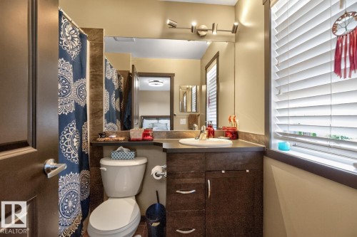 Bathroom featuring a dark wood-finish vanity with a white undermount sink, a large wall mirror, and a contemporary track light fixture - 3627 12 Street Nw, Edmonton, AB - Indoor Photo Showing Bathroom