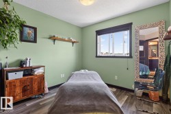 Bedroom with light green walls and wood-finish flooring - 