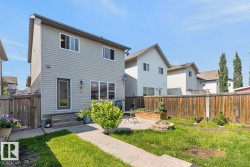 Private backyard featuring a paved patio area with a built-in fire pit, raised garden bed, and wood privacy fencing - 