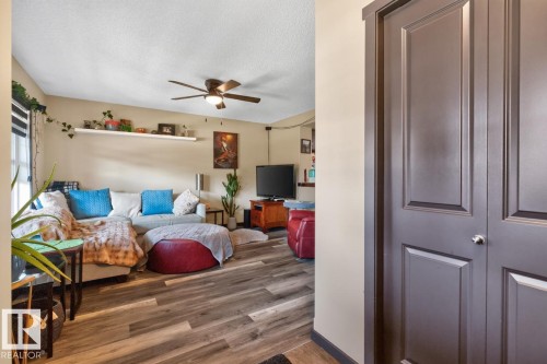 Living area featuring wood-finish flooring, a ceiling fan with integrated lighting, and a white floating wall shelf - 3627 12 Street Nw, Edmonton, AB - Indoor