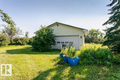 Detached garage featuring a white overhead door, light-colored siding, and a gabled roofline - 55319 Rge Road 222, Rural Sturgeon County, AB 