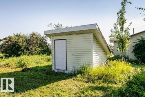 Detached utility shed featuring light-colored siding, a white panel door, and a sloped roof - 55319 Rge Road 222, Rural Sturgeon County, AB 