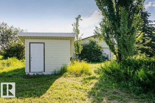 Exterior storage shed featuring light-colored siding and a white paneled door - 55319 Rge Road 222, Rural Sturgeon County, AB 
